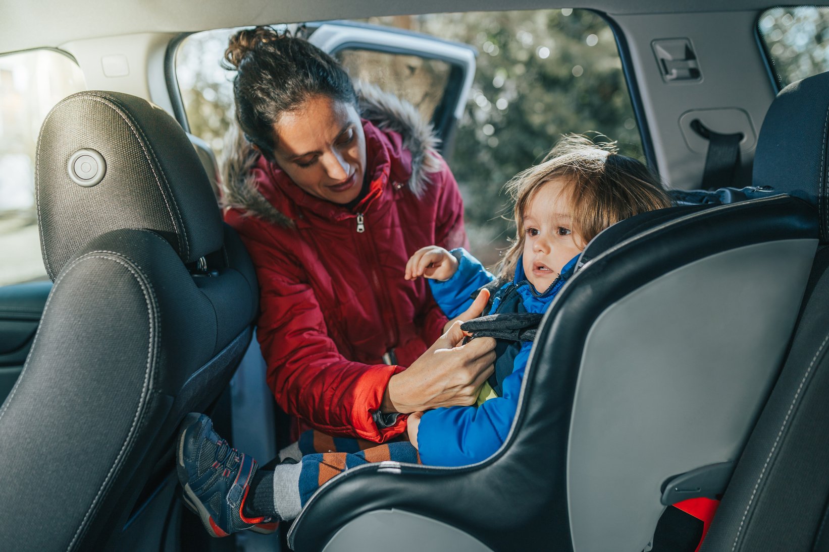 Woman putting child in car seat